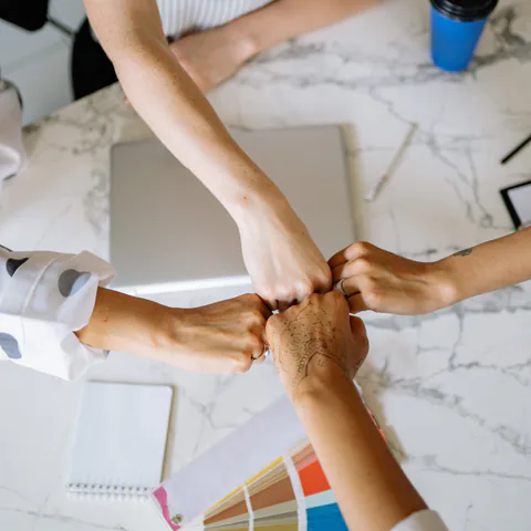 Manos de un equipo de trabajo unidas sobre una mesa